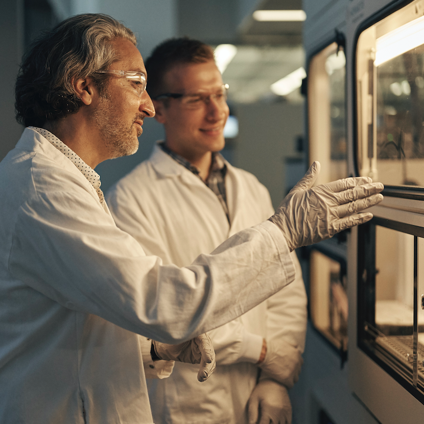 Image of a male scientist speaking to another scientist in a lab.